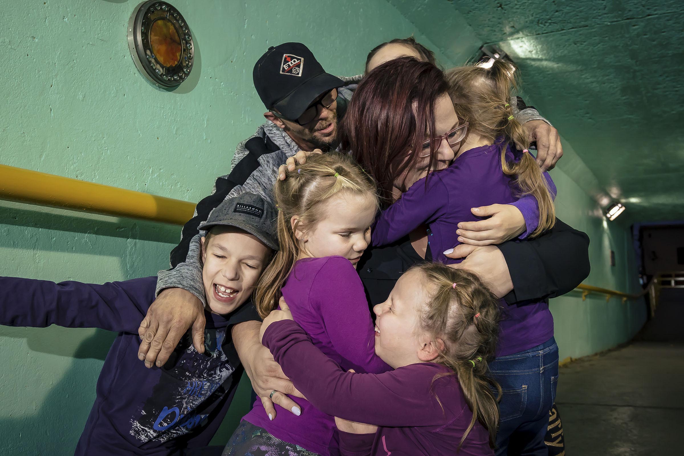 Portrait famille avec cinq enfants comprenant quatre filles et un garçon qui se donne un câlin dand un tunnel milieu urbain par Tobi Malette photographe Vaudreuil-Soulanges et ouest de l'ile de montreal