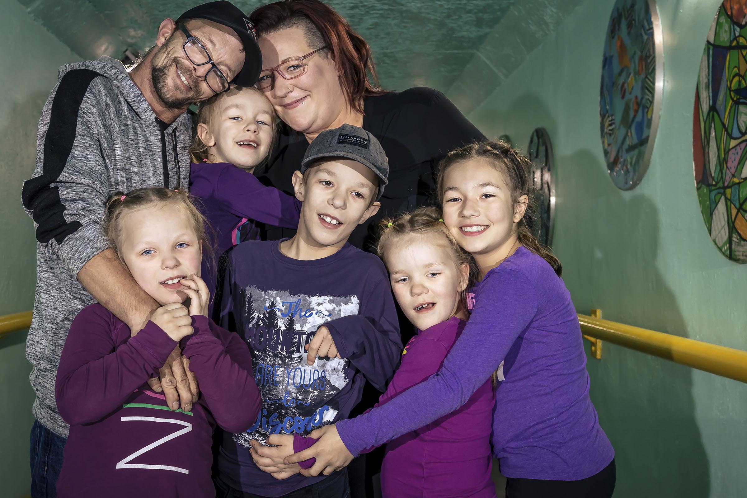 Portrait famille avec cinq enfants comprenant quatre filles et un garçon se donne un câlin dans un tunnel milieu urbain par Tobi Malette photographe Vaudreuil-Soulanges et ouest de l'ile de montreal