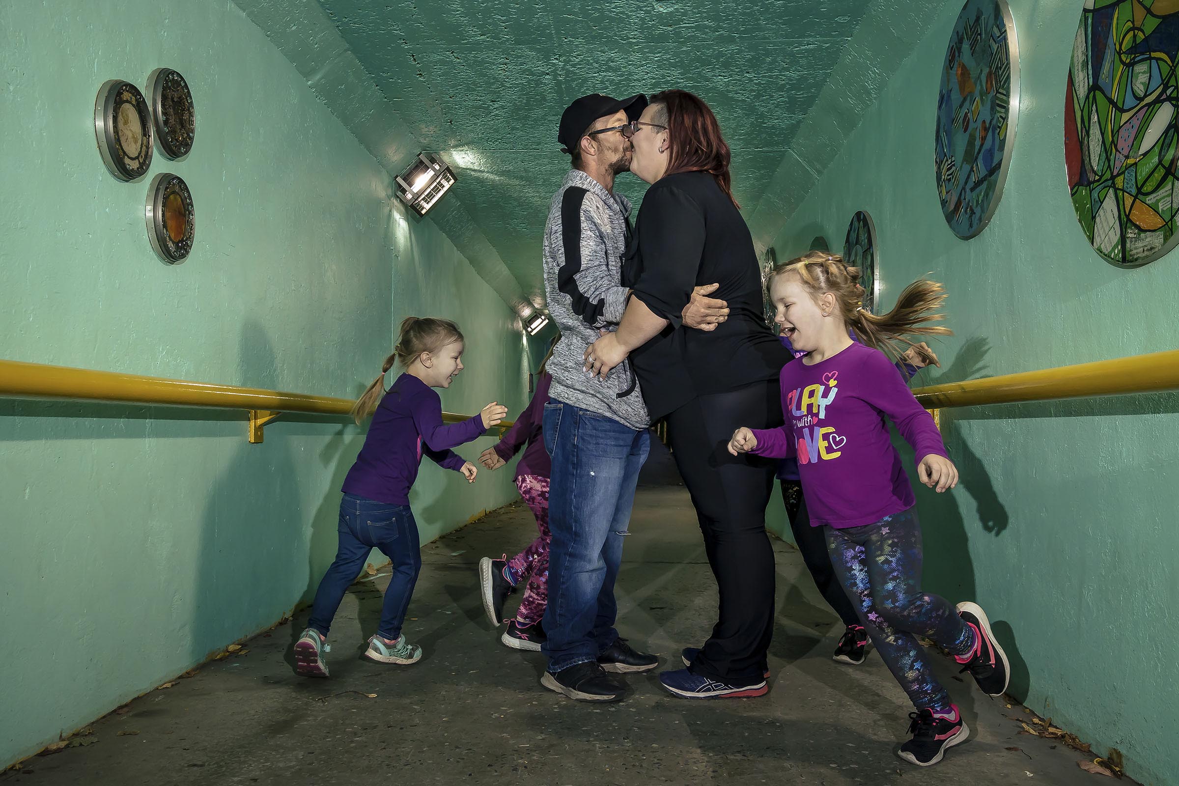 Portrait famille enfants qui courent autour de leurs parents dans un tunnel milieu urbain par Tobi Malette photographe Vaudreuil-Soulanges et ouest de l'ile de montreal