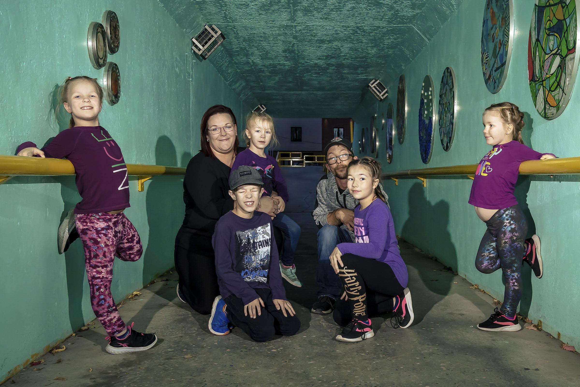 Portrait famille avec cinq enfants comprenant quatre filles et un garçon font la pose dans un tunnel milieu urbain par Tobi Malette photographe Vaudreuil-Soulanges et ouest de l'ile de montreal