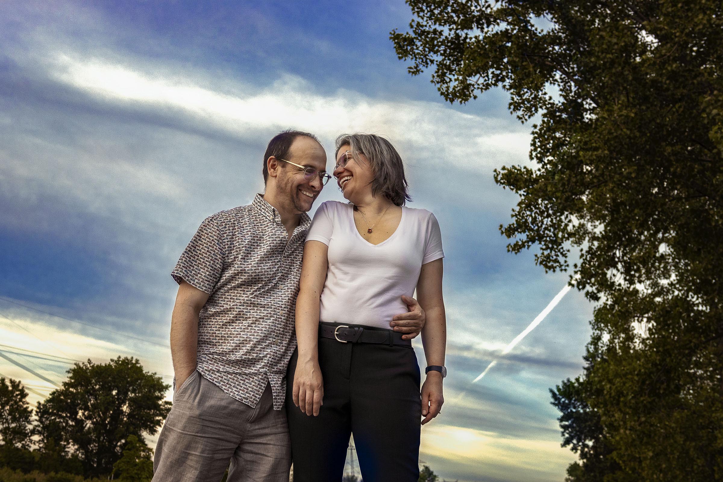 Portrait couple femme homme sourit et rit dehors avec un ciel bleu par Tobi Malette photographe Vaudreuil-Soulanges et ouest de l'ile de montreal