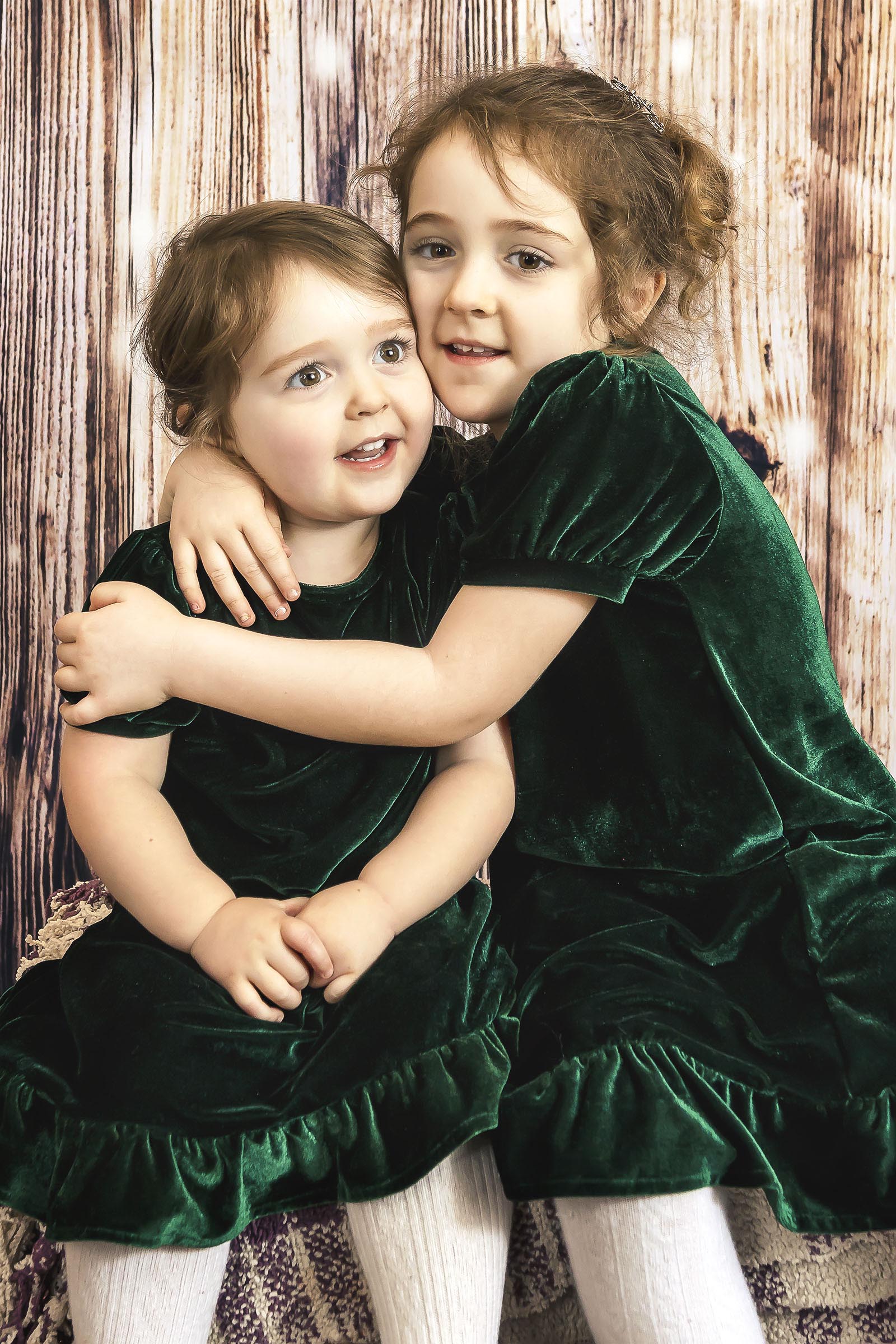 Beaux-arts portrait deux jeunes filles portant robes vertes en velours se donnent un câlin en studio mur bois par Tobi Malette photographe Vaudreuil-Soulanges et ouest de l'ile de montreal